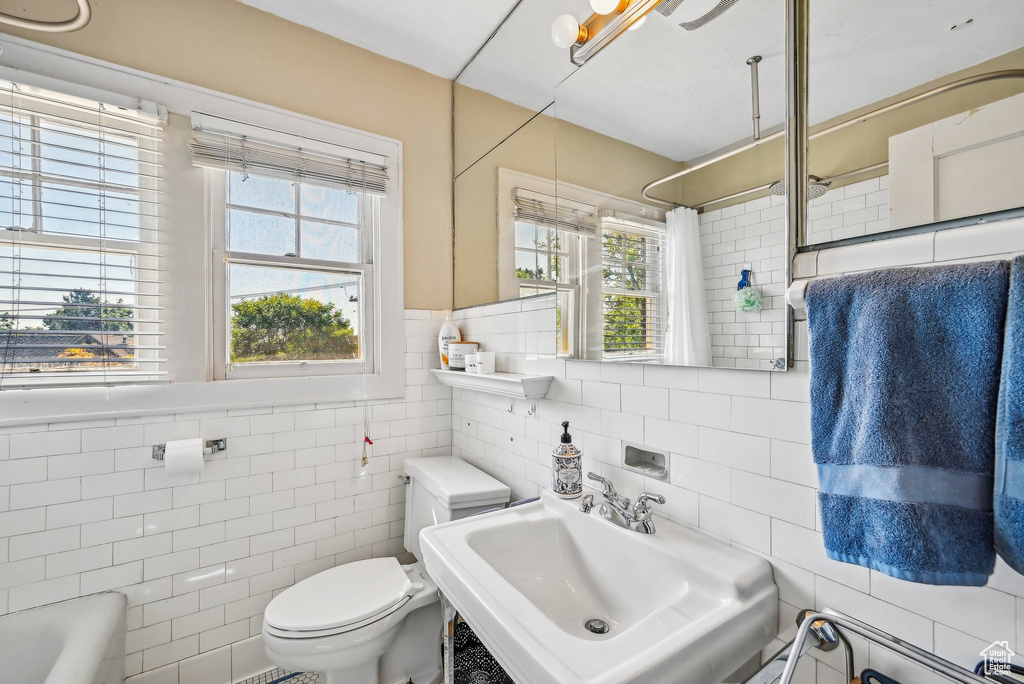Full bathroom featuring tile walls, a sink, toilet, healthy amount of natural light, and a shower with curtain