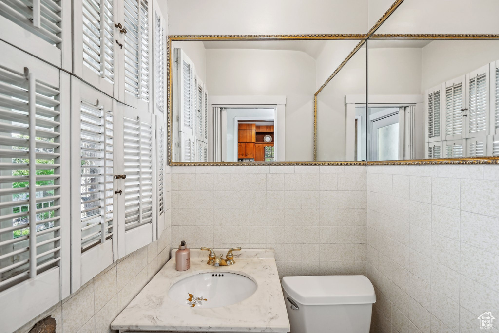 Bathroom featuring tile walls, toilet, and vanity