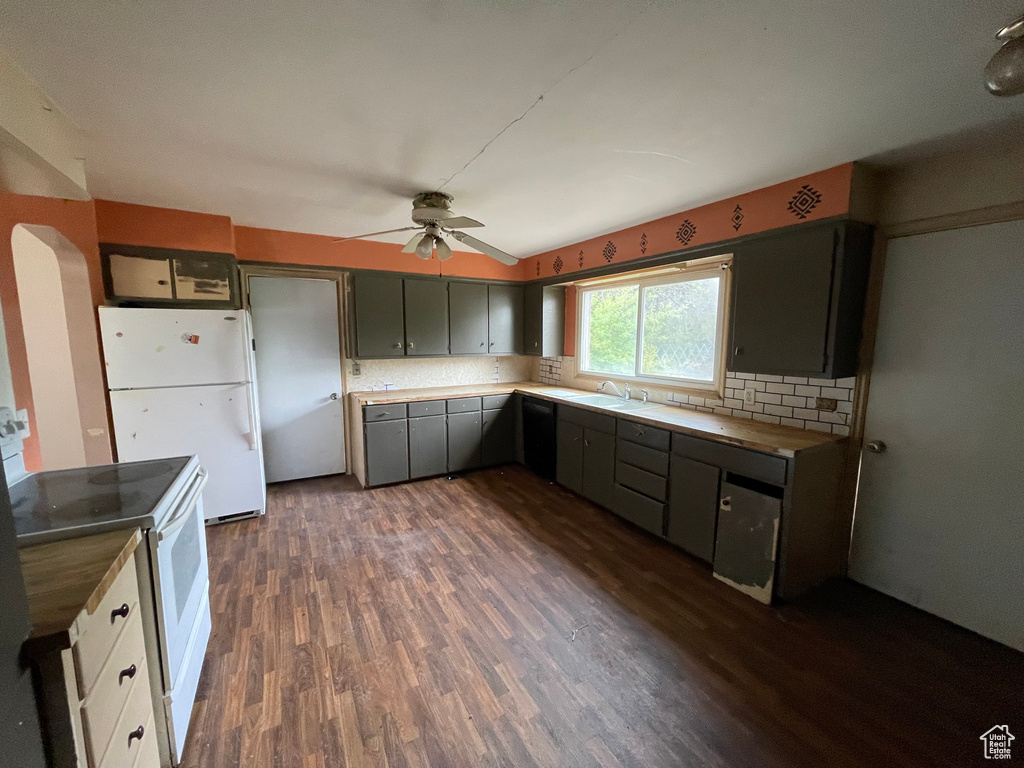 Kitchen with white appliances, a sink, ceiling fan, dark wood-style flooring, and tasteful backsplash