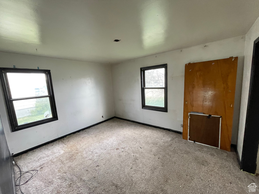 Spare room featuring carpet flooring and baseboards