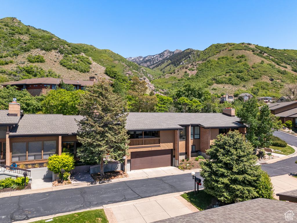 View of front of property featuring a mountain view, a garage, concrete driveway, and a balcony