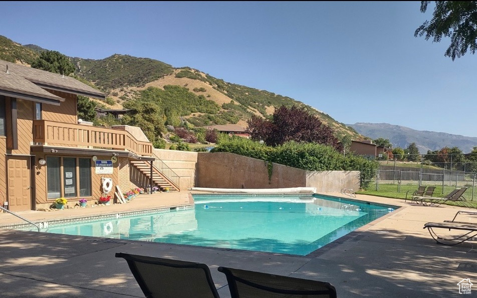 Community pool with a mountain view, a fenced backyard, a patio area, and stairway