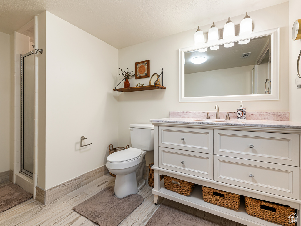 Full bathroom with vanity, wood finished floors, toilet, and a shower with door