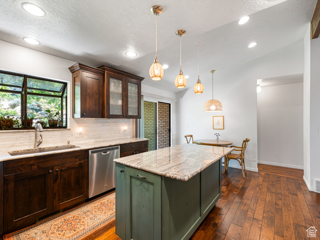 Kitchen with dishwasher, a sink, green cabinets, backsplash, and dark wood-type flooring