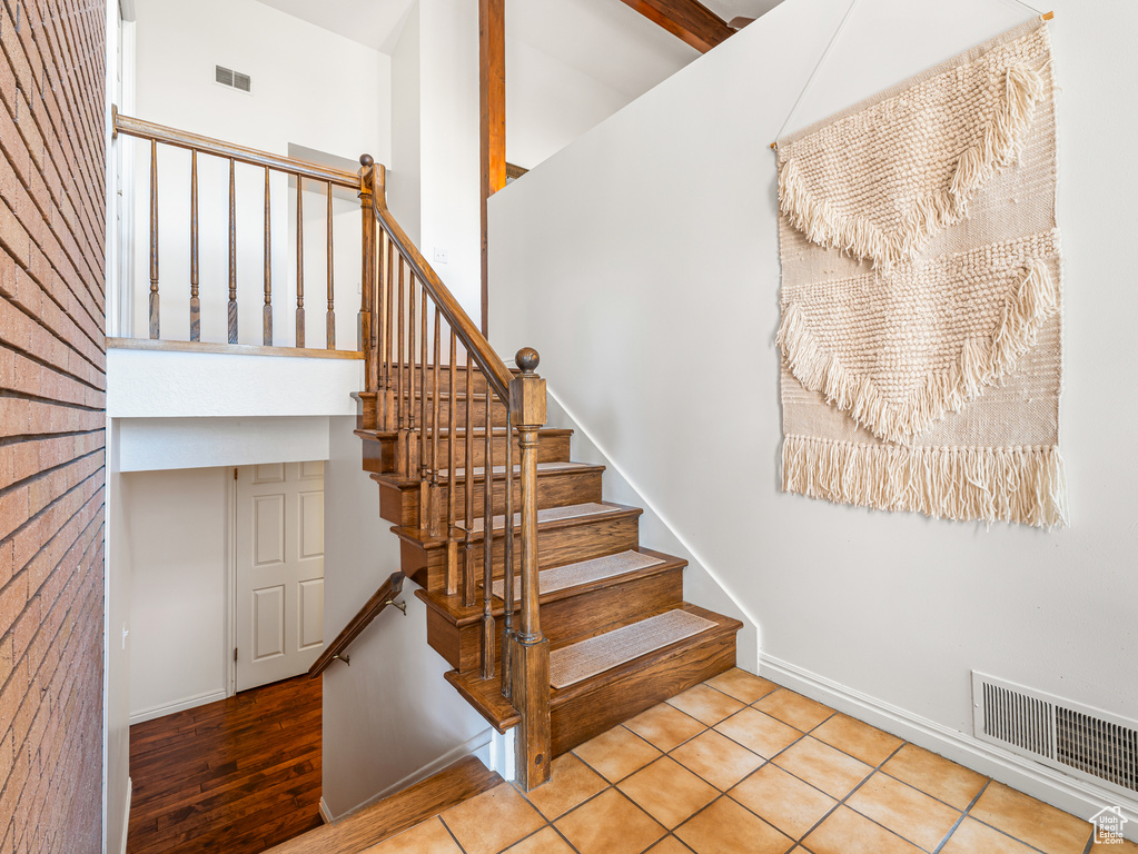 Stairs with a towering ceiling, baseboards, and tile patterned floors