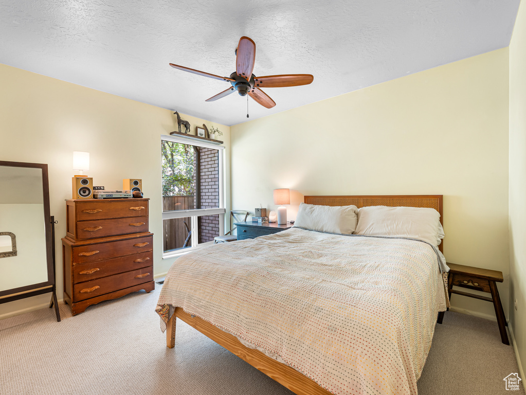 Bedroom with light carpet, baseboards, a ceiling fan, and a textured ceiling