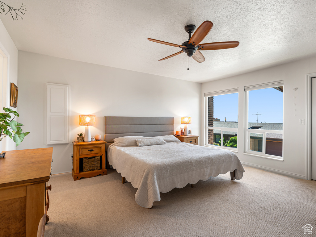 Bedroom featuring light carpet, a ceiling fan, baseboards, and a textured ceiling