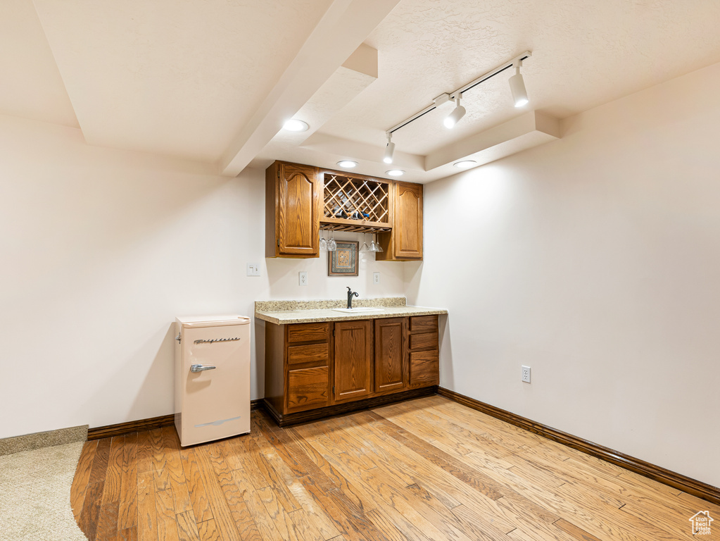 Indoor wet bar featuring baseboards, track lighting, and light wood-type flooring