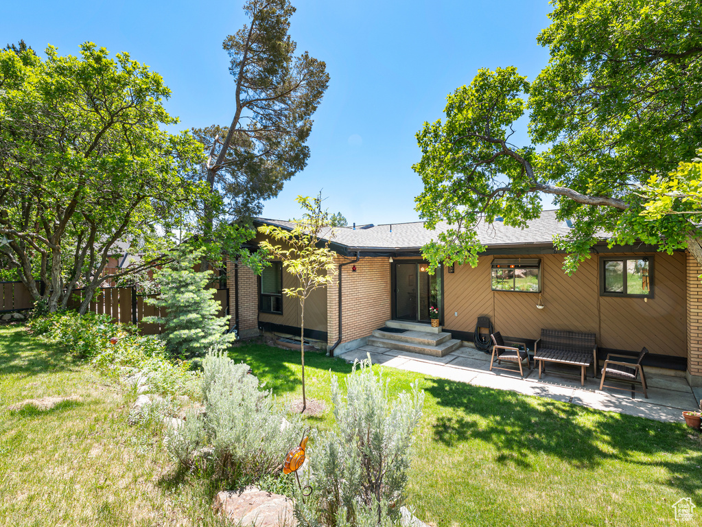 Back of property featuring a patio area, brick siding, and a shingled roof