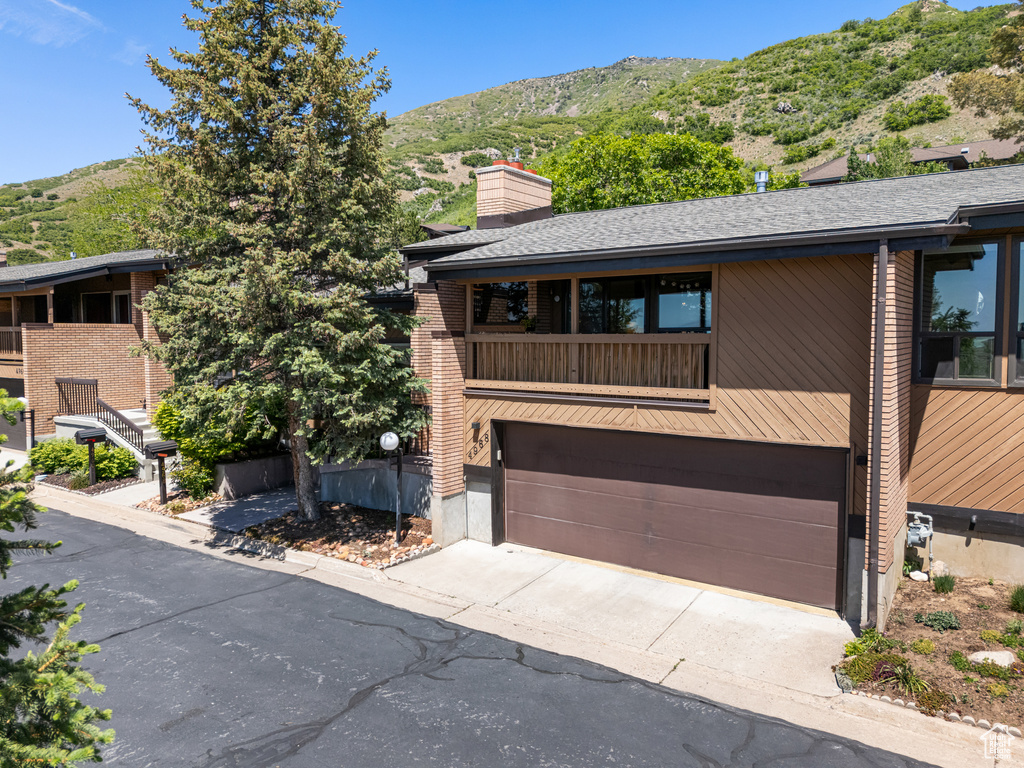 View of front of house featuring an attached garage, a mountain view, driveway, and a chimney