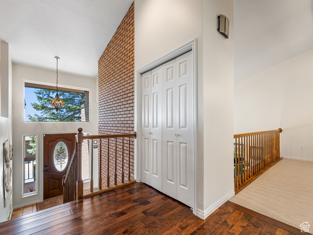 Foyer entrance with wood finished floors, a chandelier, a high ceiling, and baseboards