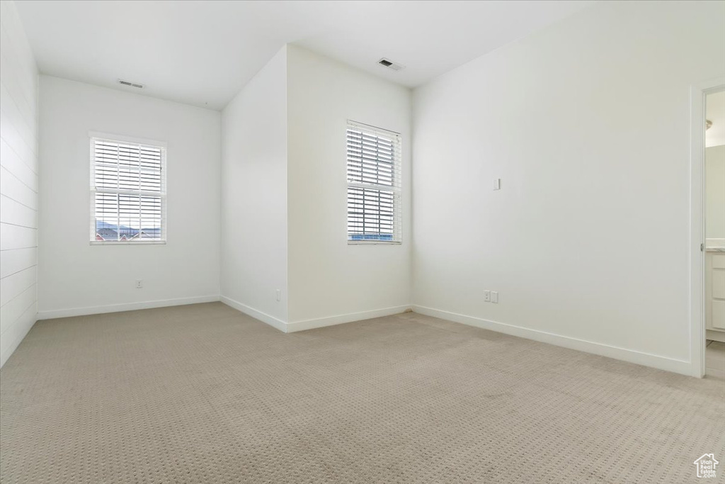 Empty room with light colored carpet, plenty of natural light, and baseboards