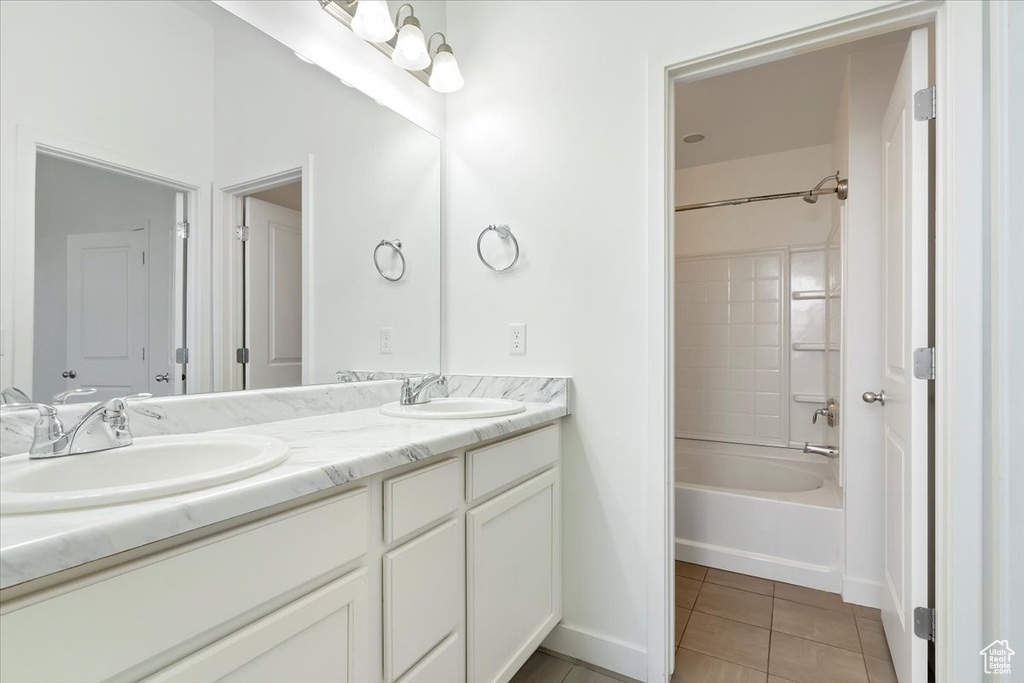 Full bath with tile patterned flooring, double vanity, bathing tub / shower combination, and baseboards