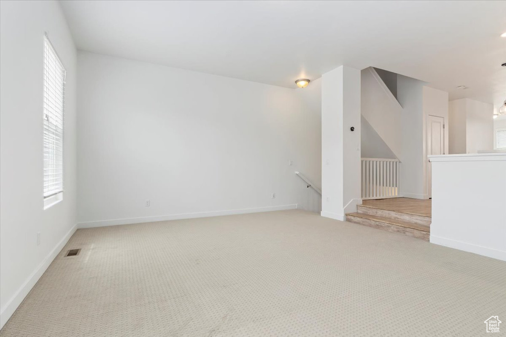 Unfurnished room featuring light carpet, baseboards, and healthy amount of natural light