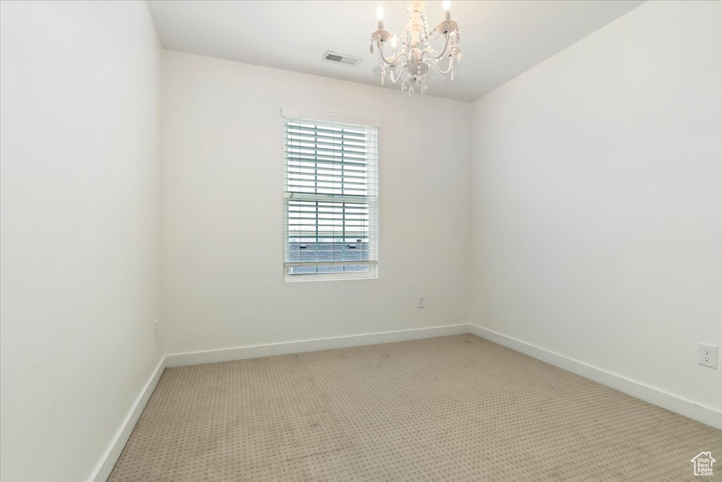 Unfurnished room with a chandelier, carpet flooring, and baseboards