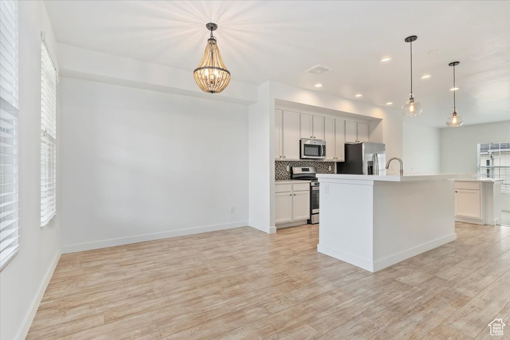 Kitchen with stainless steel appliances, backsplash, a sink, light wood-style floors, and recessed lighting