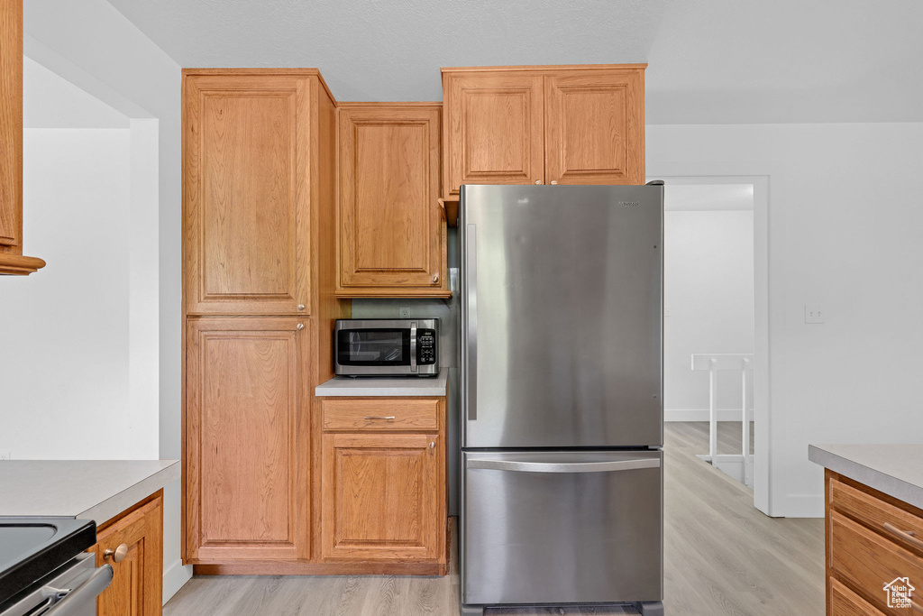Kitchen with appliances with stainless steel finishes, light wood-type flooring, and light countertops