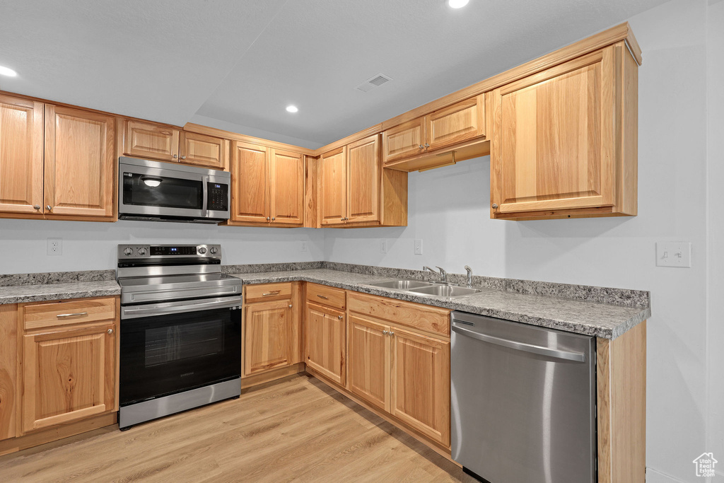 Kitchen featuring stainless steel appliances, a sink, light wood-type flooring, recessed lighting, and light countertops