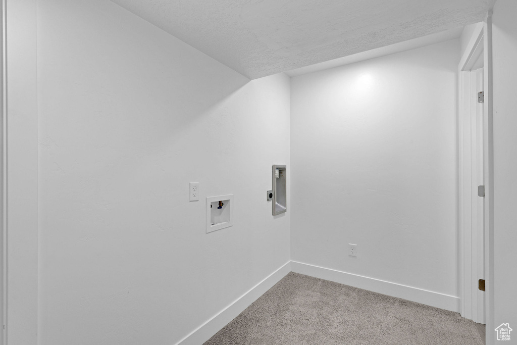 Laundry area with light carpet, hookup for an electric dryer, baseboards, washer hookup, and a textured ceiling