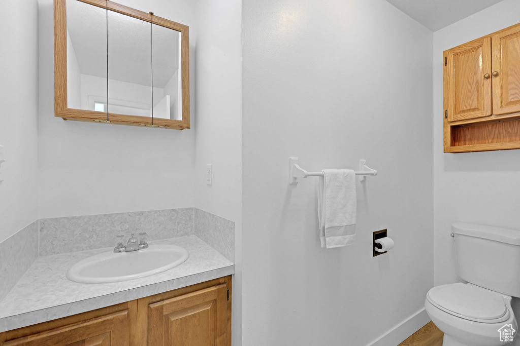 Half bath featuring toilet, vanity, and baseboards