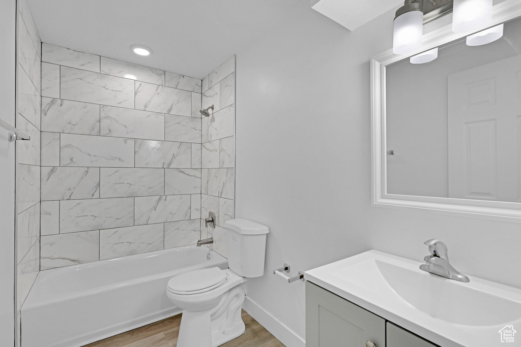 Bathroom featuring wood finished floors, vanity, toilet, and  shower combination