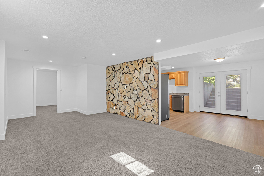 Unfurnished living room with light colored carpet, baseboards, recessed lighting, and a textured ceiling