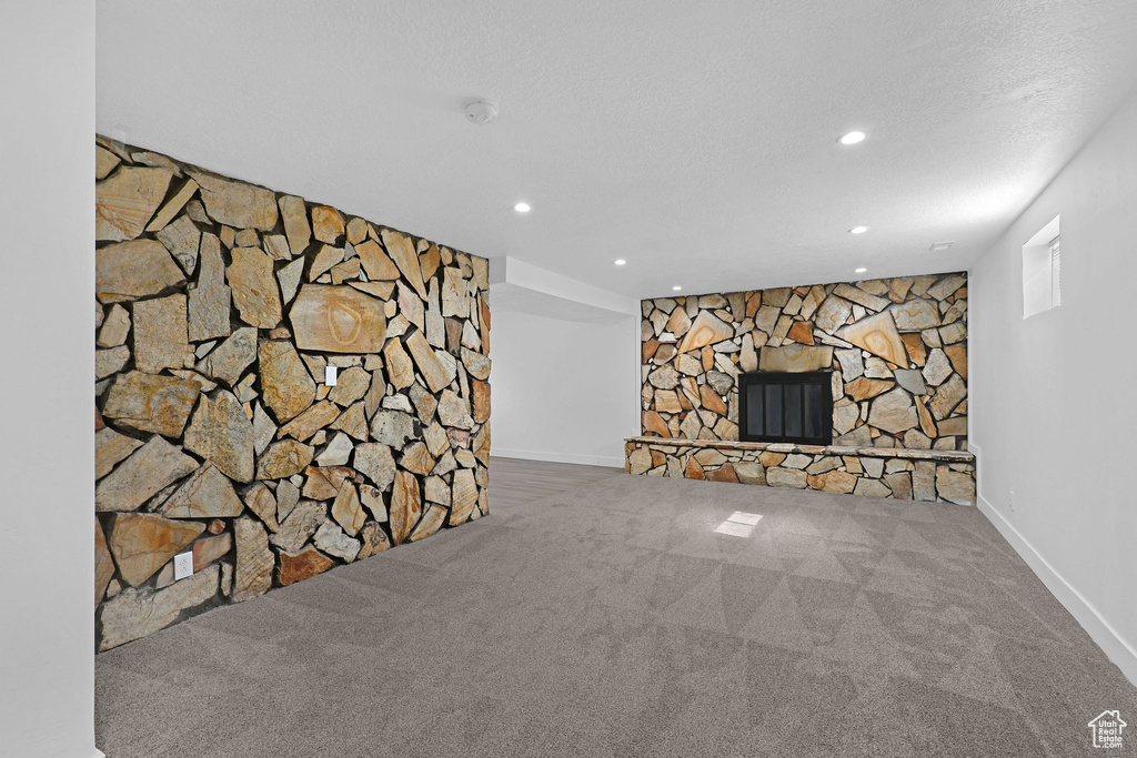 Unfurnished living room featuring carpet flooring, recessed lighting, baseboards, and a fireplace