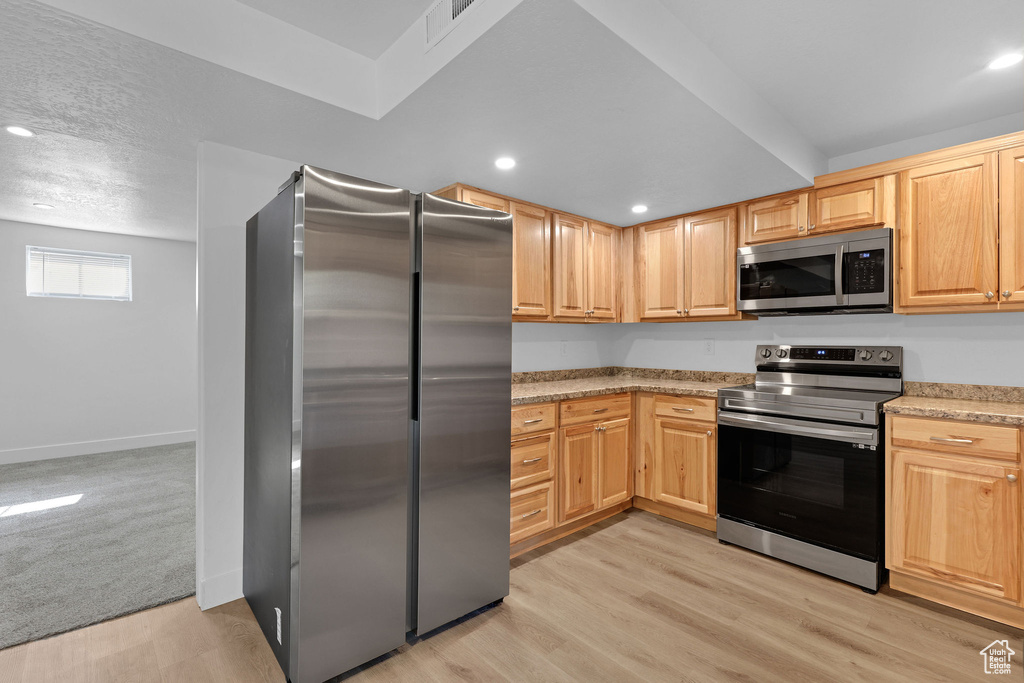 Kitchen with stainless steel appliances, light wood-style flooring, light brown cabinets, recessed lighting, and baseboards