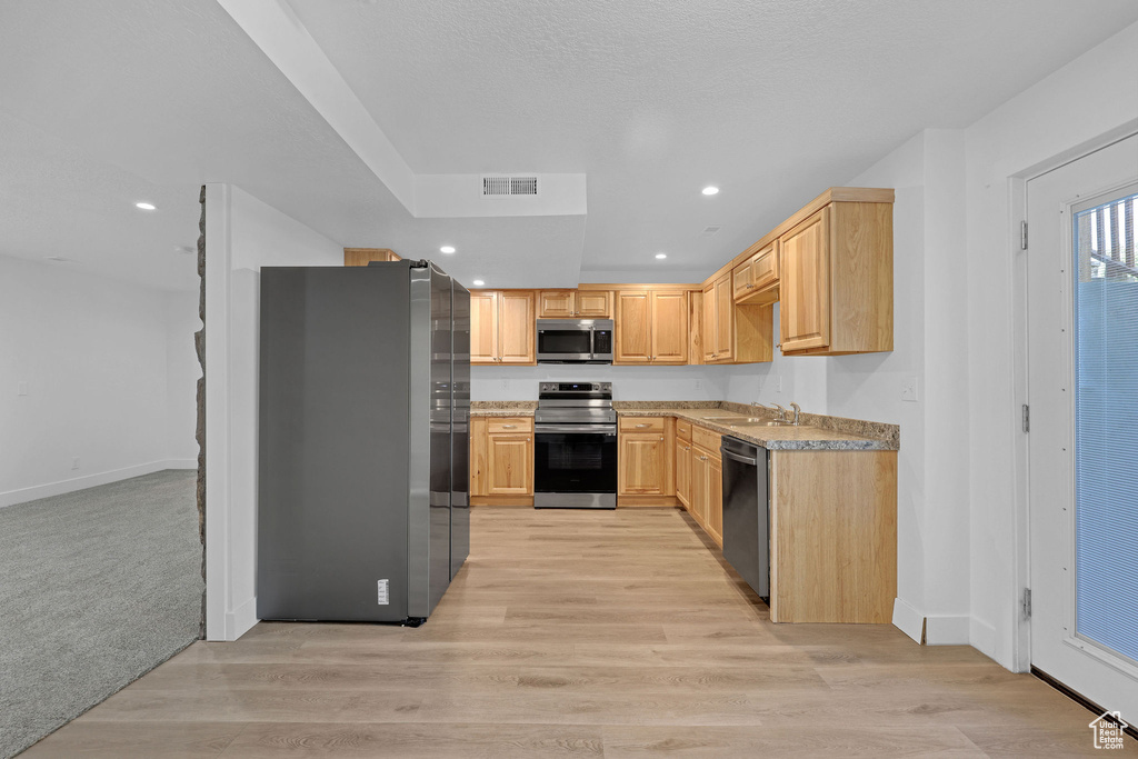 Kitchen featuring appliances with stainless steel finishes, a sink, light brown cabinets, recessed lighting, and light countertops