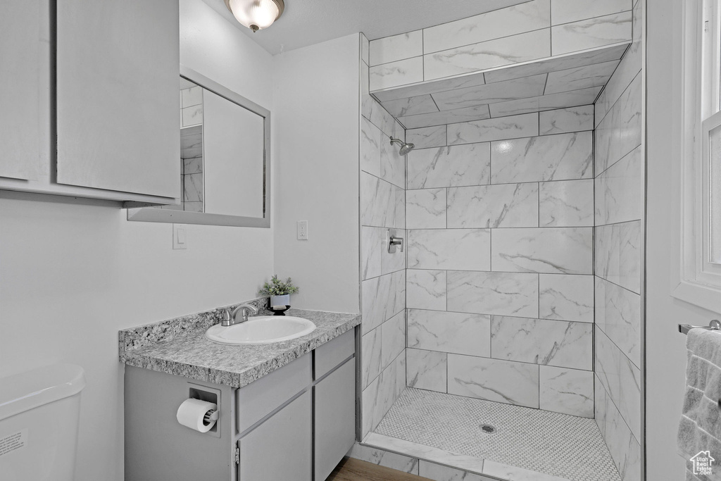 Bathroom featuring toilet, vanity, and a tile shower