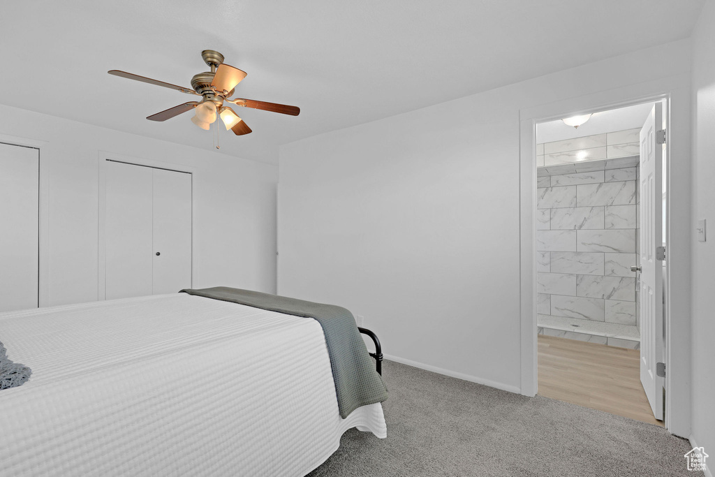 Bedroom with ensuite bathroom, baseboards, light carpet, and ceiling fan