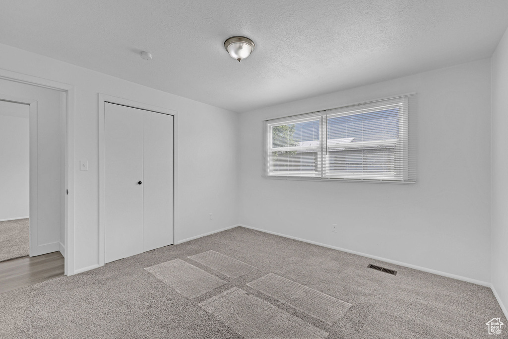 Unfurnished bedroom featuring carpet, a closet, baseboards, and a textured ceiling