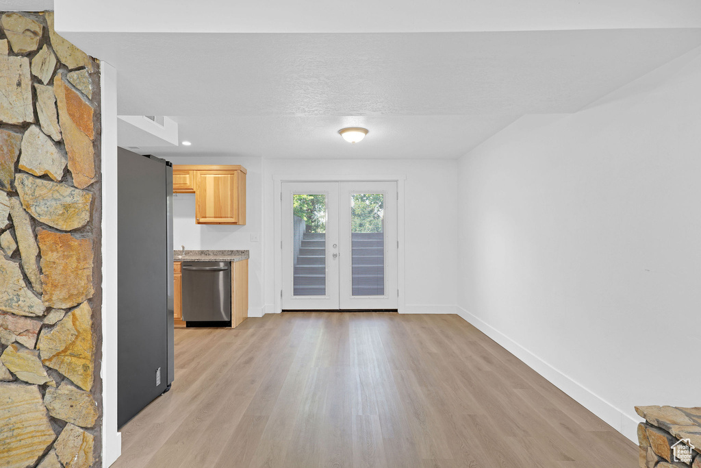 Unfurnished living room featuring light wood-type flooring and baseboards