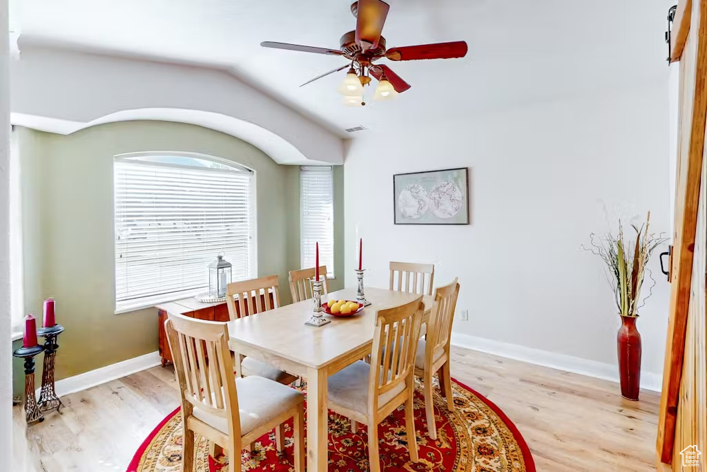 Dining room with light wood-type flooring, vaulted ceiling, a ceiling fan, and baseboards