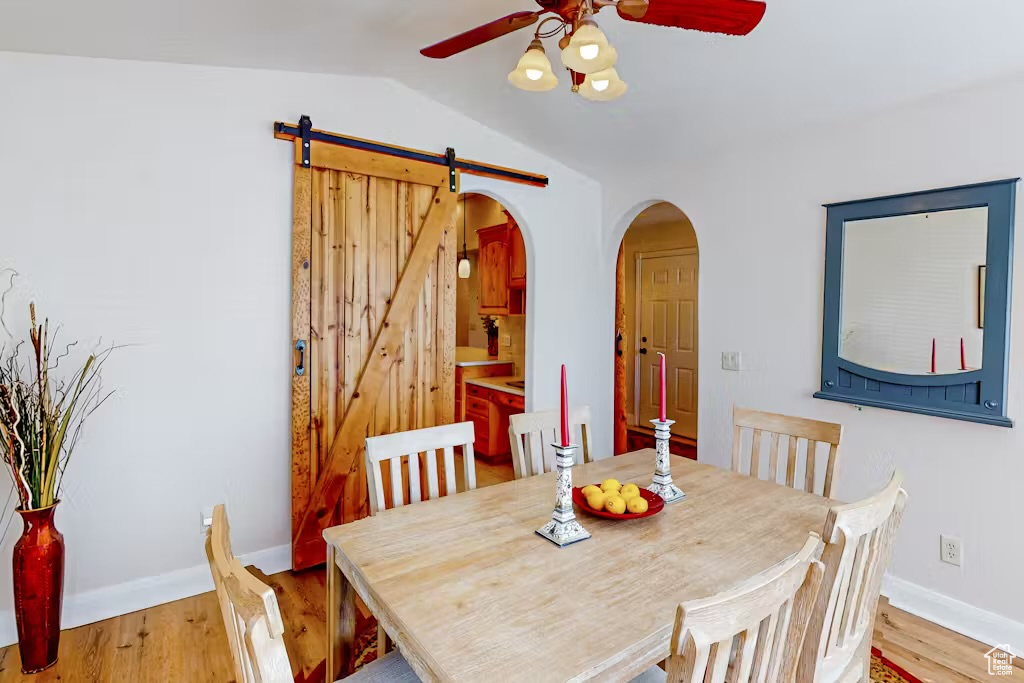 Dining area with ceiling fan, arched walkways, lofted ceiling, baseboards, and wood finished floors