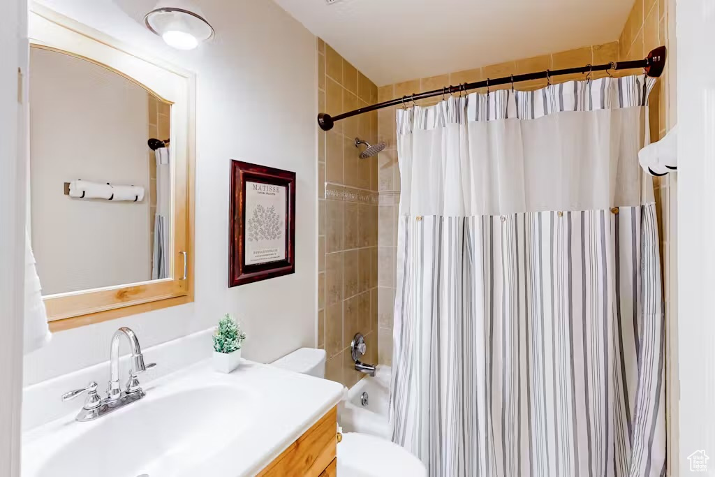 Full bathroom with toilet, vanity, and shower / bath combination with curtain