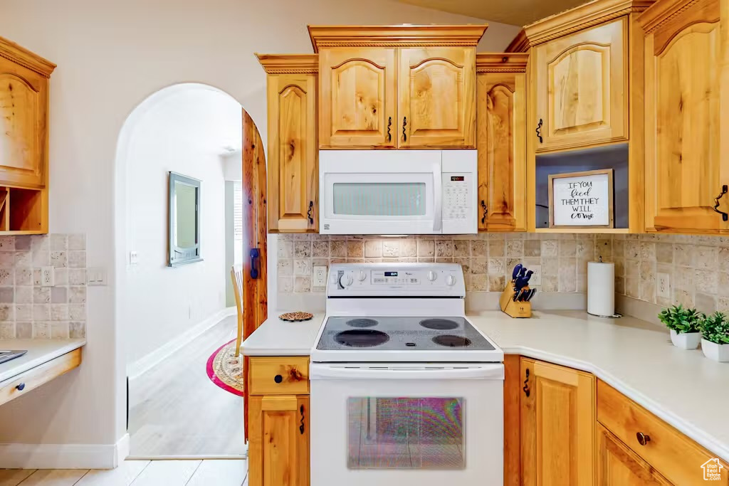 Kitchen featuring white appliances, light countertops, tasteful backsplash, baseboards, and light tile patterned floors