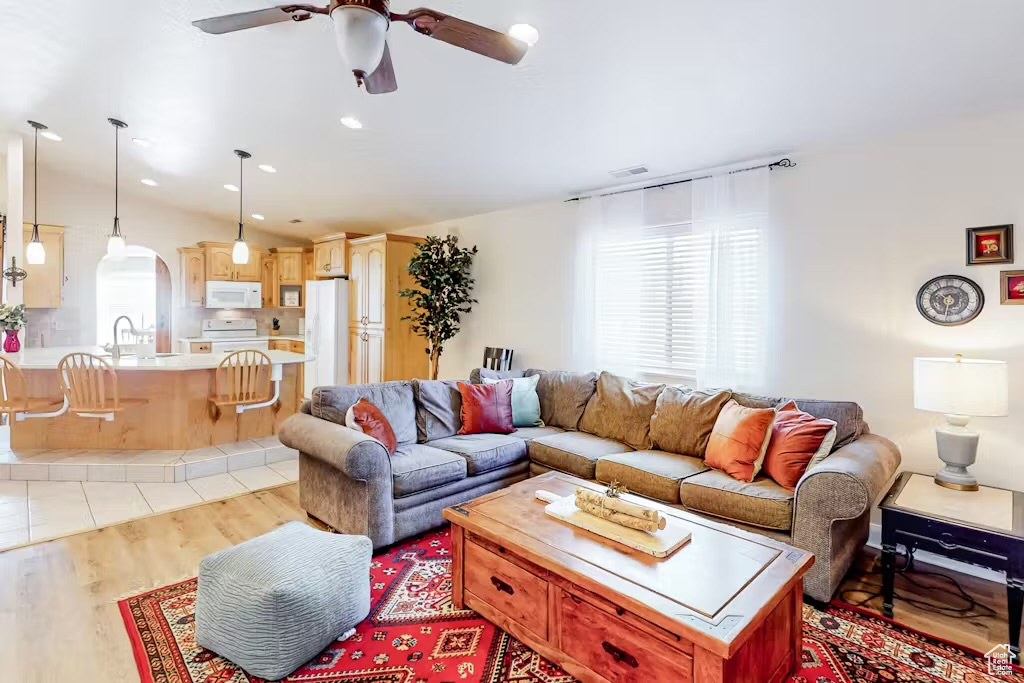 Living room featuring healthy amount of natural light, ceiling fan, arched walkways, light wood finished floors, and recessed lighting