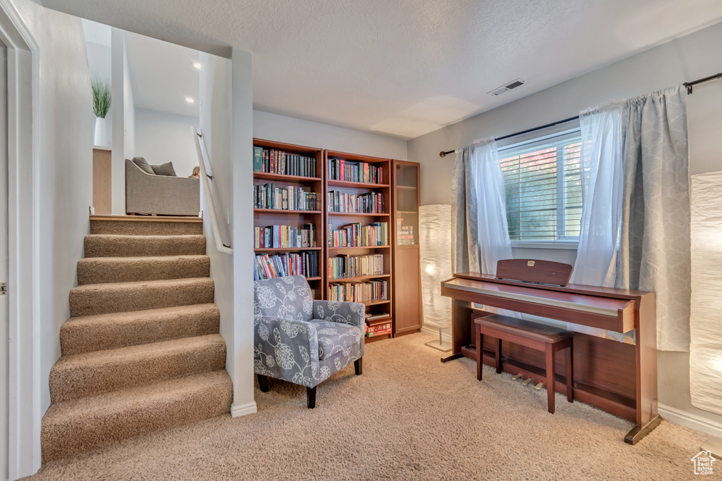 Sitting room featuring carpet floors, stairway, and a textured ceiling