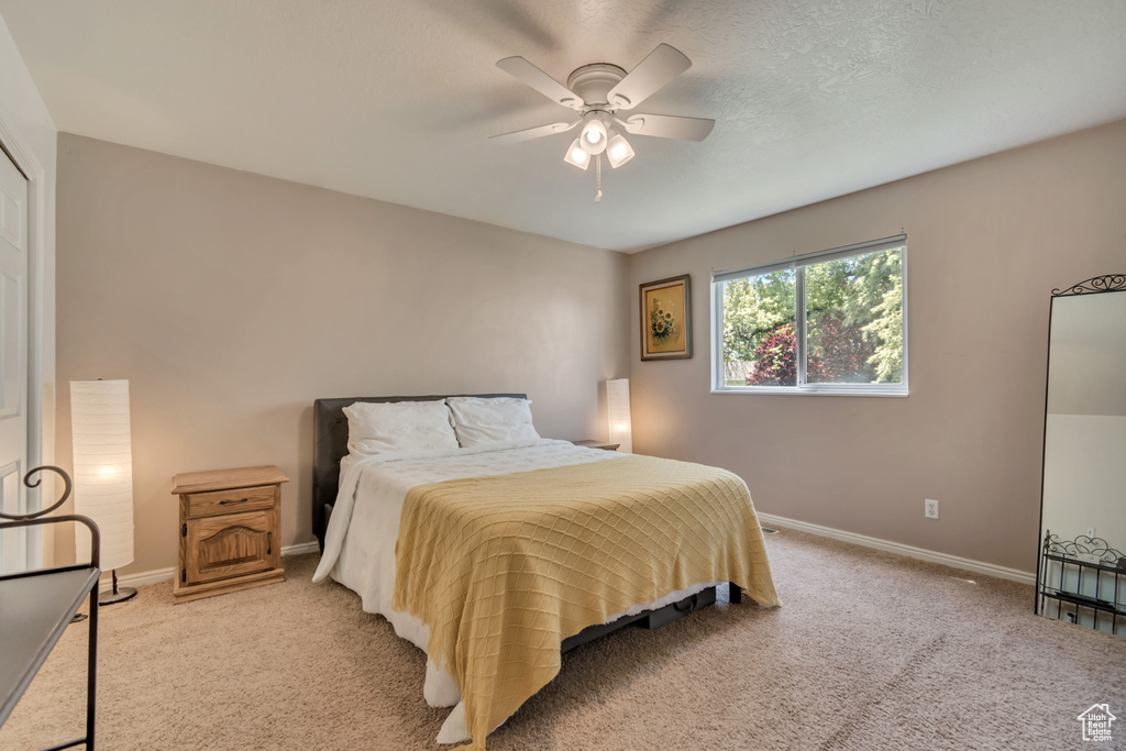 Bedroom featuring light colored carpet, baseboards, and ceiling fan