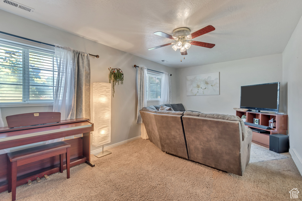 Living area with carpet flooring, a ceiling fan, and baseboards