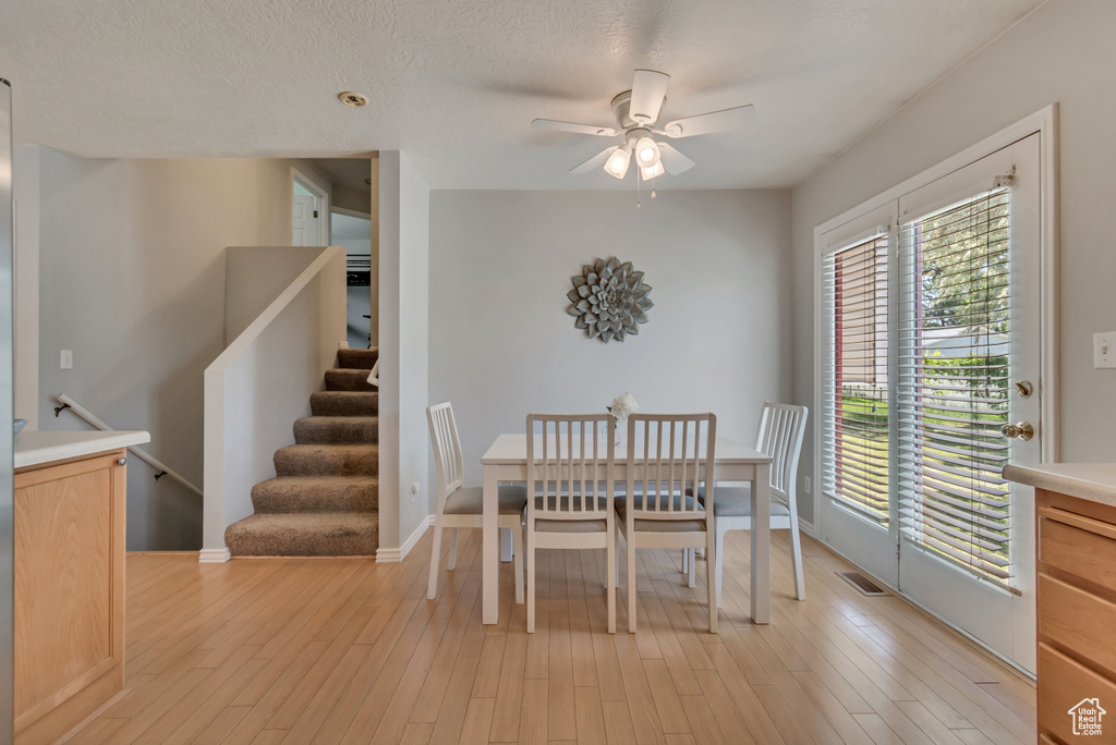 Dining room featuring a ceiling fan, light wood-style floors, stairway, and baseboards