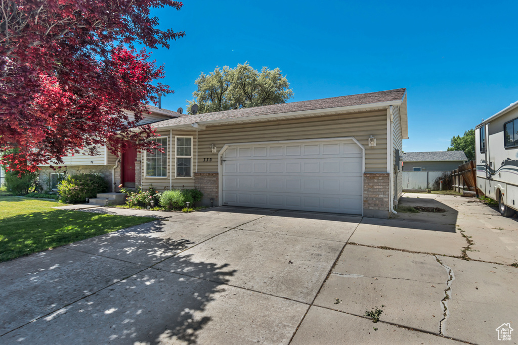 View of front of property with brick siding, driveway, a garage, and a front yard