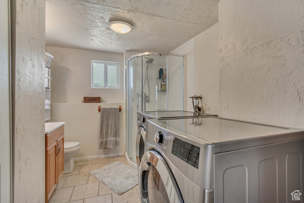 Bathroom featuring a shower stall, vanity, toilet, a textured ceiling, and tile patterned flooring
