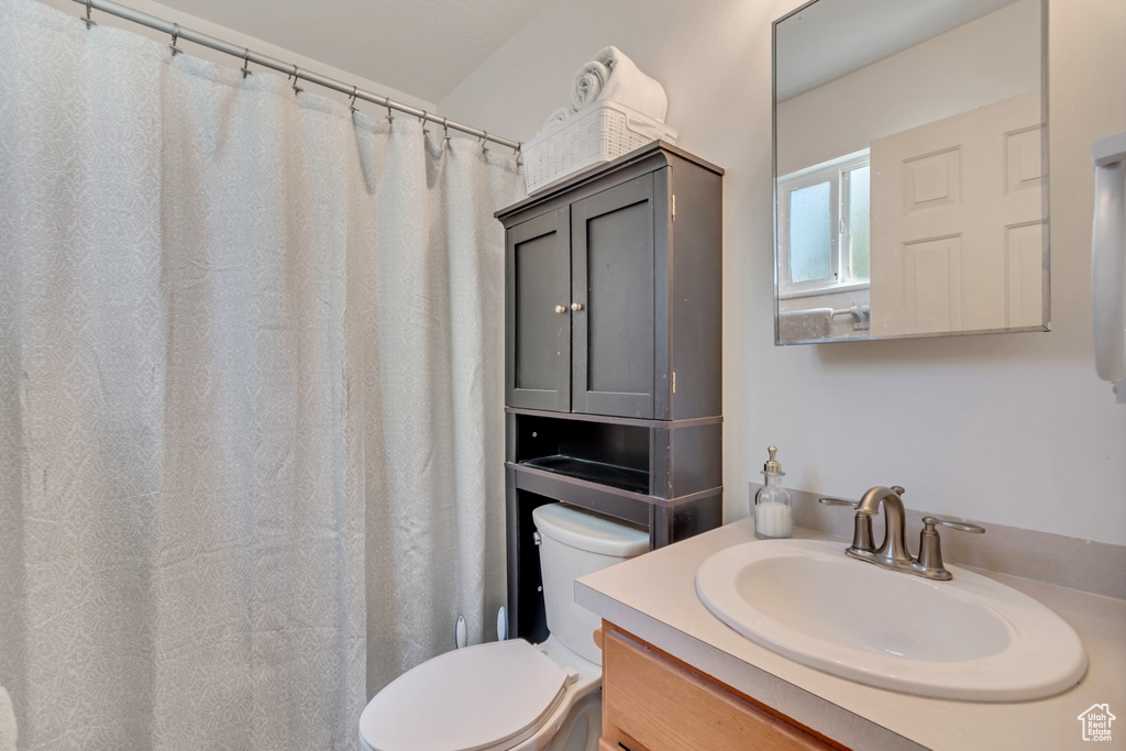 Bathroom with toilet, vanity, and a shower with curtain