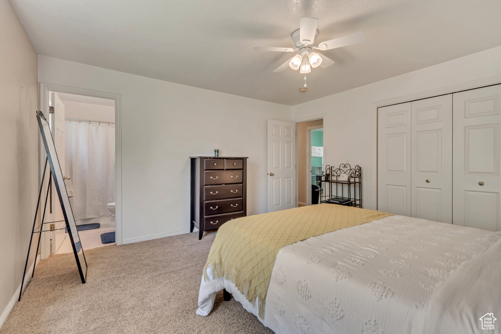 Carpeted bedroom featuring a closet, baseboards, ensuite bath, and a ceiling fan