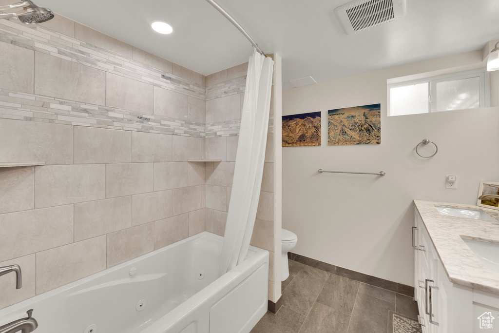 Full bath featuring toilet, a combined bath / shower with jetted tub, baseboards, and double vanity