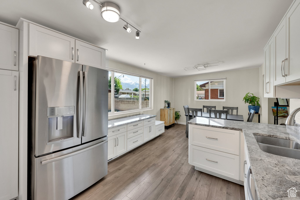 Kitchen featuring stainless steel fridge with ice dispenser, a sink, a peninsula, and white cabinets