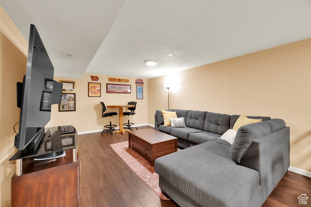 Living room with baseboards, wood finished floors, and a textured ceiling
