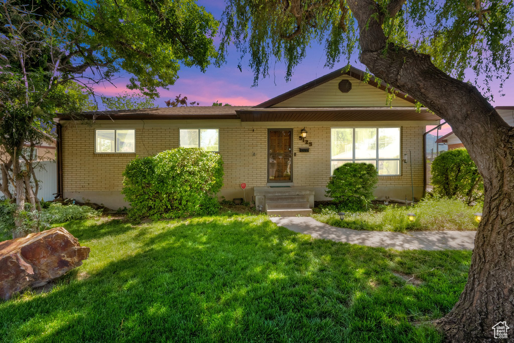 Single story home with brick siding and a front yard